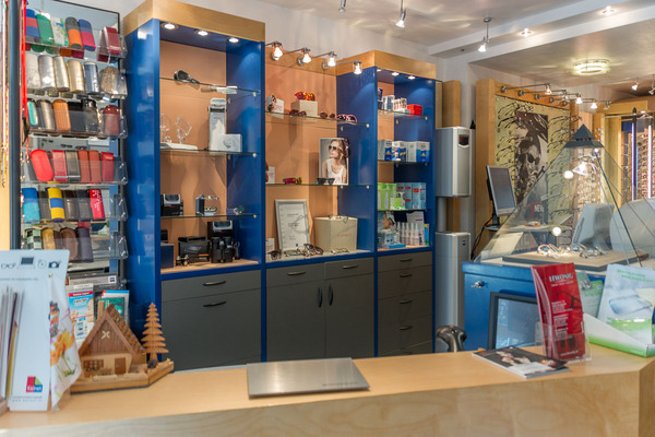 Optikergeschäft mit moderner Ladentheke, Brillenetuis, Pflegemitteln und Sonnenbrillen.